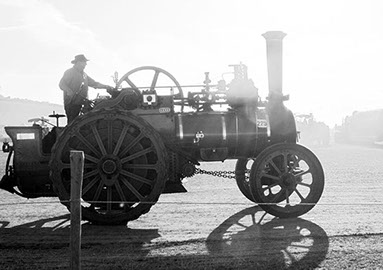 A Steam engine pulling uphill in the sunset.
